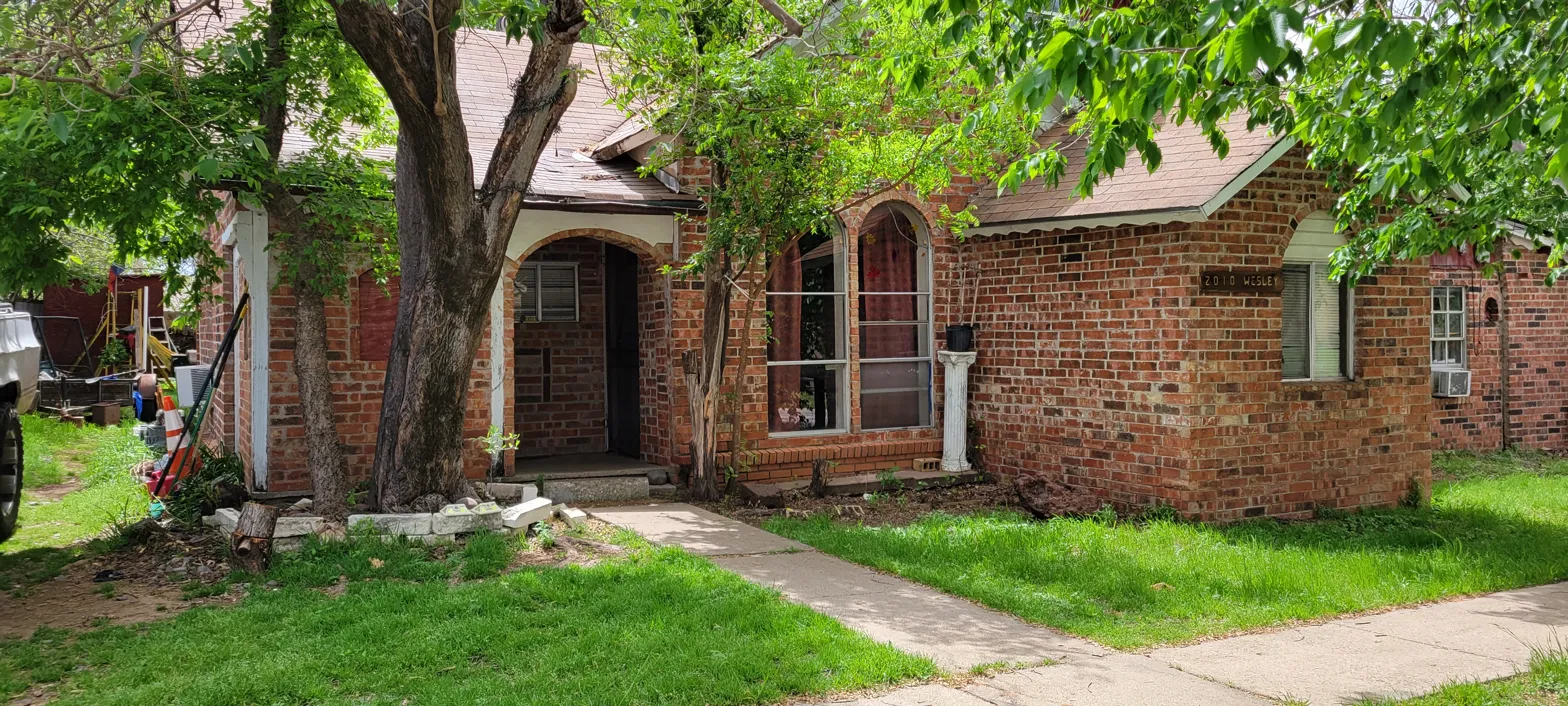 Front exterior of 2010 Wesley Dr Arlington TX before purchase — brick home with overgrown yard