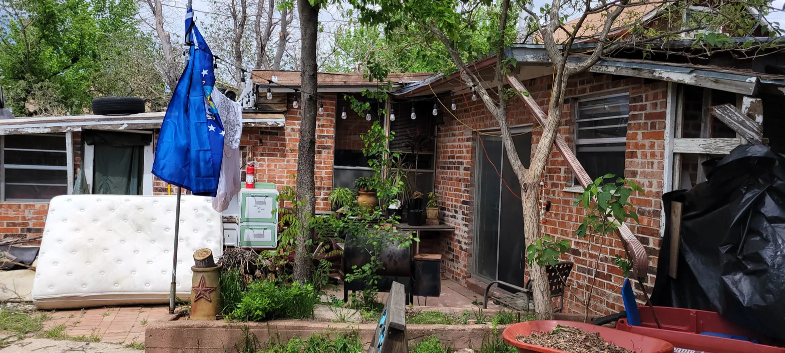 Back of 2010 Wesley Dr Arlington TX showing severe structural damage to rear porch and debris in yard